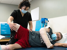 Therapist stretching leg of male amputee patient.