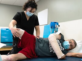 Therapist stretching leg of male amputee patient.