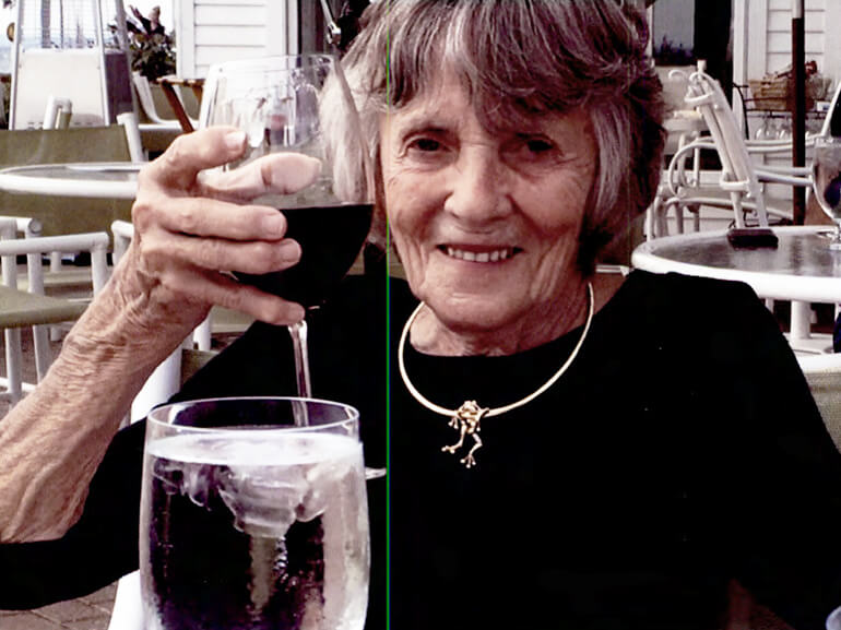 Jane raising a glass of red wine in a toast.