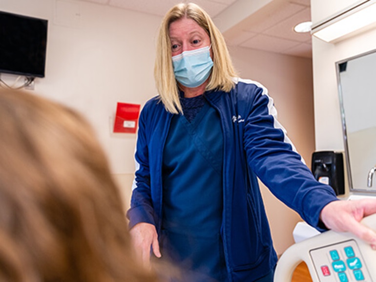 Nurse talking to a patient at bedside.
