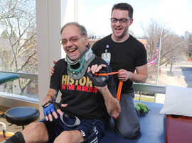 Male patient and therapist using resistance band in therapy.