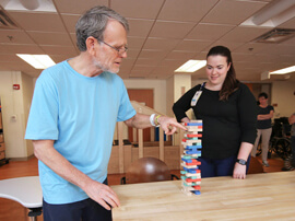 Male patient wearing blue shirt and stacking blocks on a table.