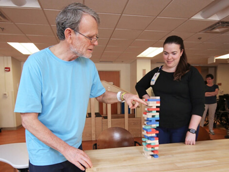 Male patient builds a tower with Jenga blocks.