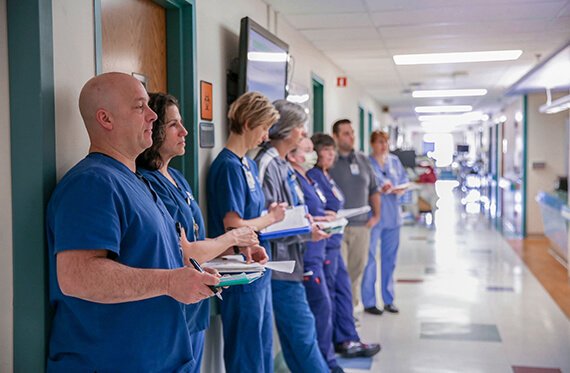 A rehabilitation team is standing along a hospital wall